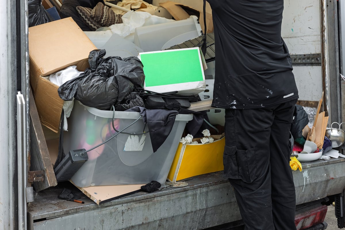 Mitarbeiter lädt Haushaltsgegenstände und Sperrmüll in ein Transporter-Heck