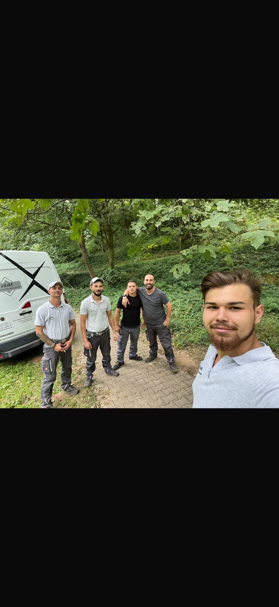 Fünf Mitarbeiter von Melix Hausmeisterservice bei einem Selfie vor einem Firmenfahrzeug im Grünen