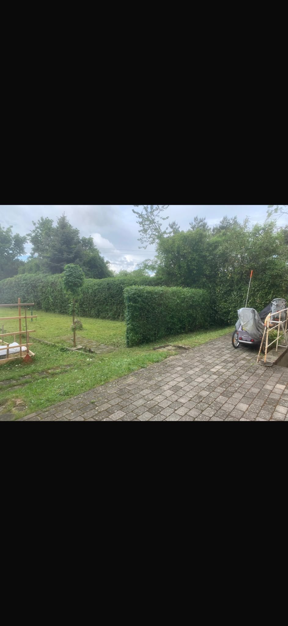 Hausgarten mit grünen Hecken, Backsteinfläche und gepflegter Rasenfläche nach der Pflege